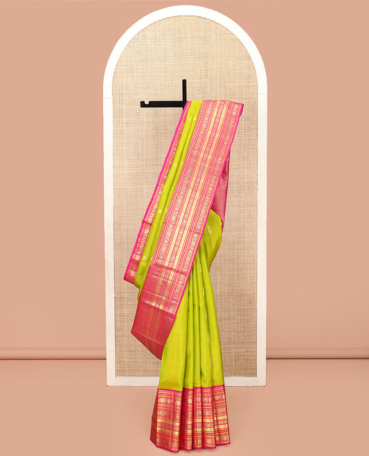 Green Vasundhara Silk Saree, Delicately Woven with Zari Buttas All Over Its Body, Complemented by Contrast Border of Thilakam Mokku, Kamalam, Iruthalai Pakshi, Yaanai, and Kamalam Designs, Vanki Design Pallu and Paired with a Contrast Blouse
