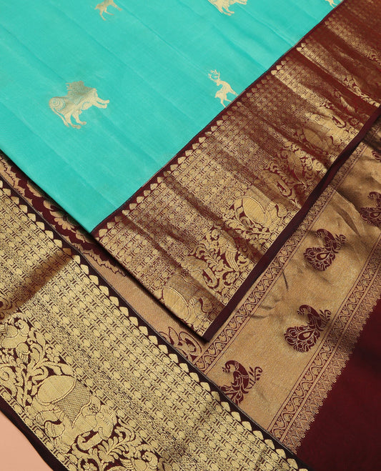Turquoise Vasundhara Lite Silk Mix Saree Enthralled with Pichwai Cow and Maan Buttas, Featuring a Contrast Border of Thilakam Mokku, Paisa, Kili, and Yaanai Designs, Zari Elevated Pallu of Mayil Designs, and a Contrast Blouse