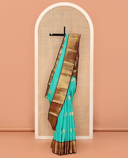 Turquoise Vasundhara Lite Silk Mix Saree Enthralled with Pichwai Cow and Maan Buttas, Featuring a Contrast Border of Thilakam Mokku, Paisa, Kili, and Yaanai Designs, Zari Elevated Pallu of Mayil Designs, and a Contrast Blouse