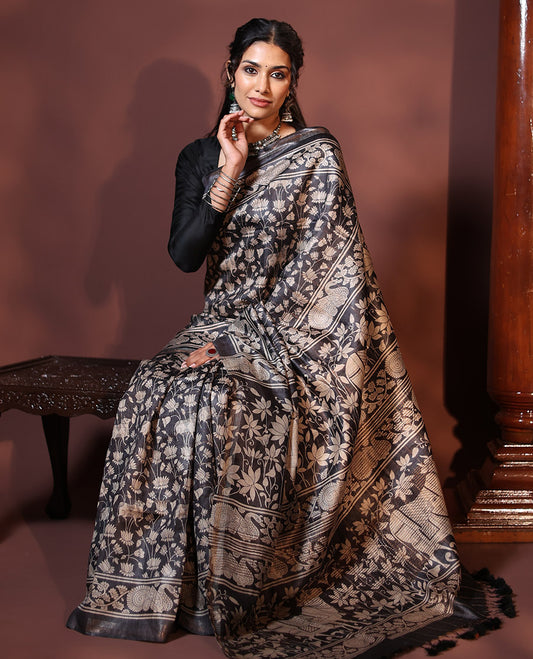 Black Tussar Saree Artfully Printed with Pichwai Cow and Lotus Motifs All Over Its Body, Subtly Made Self-Border of Kalamkari Floral-Peacock Print, Pallu Mirroring Pichwai Cow-Lotus Print, and Paired with a Plain Blouse