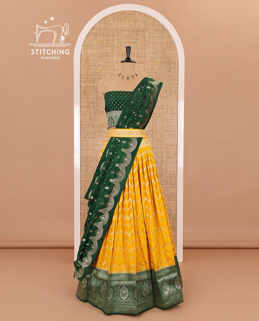 Haldi yellow chiniya crepe half-saree, chevron zari jacquard with contrast intricate patterned stone work bordered skirt, contrast blouse, and a scallop bordered intricate dhavani