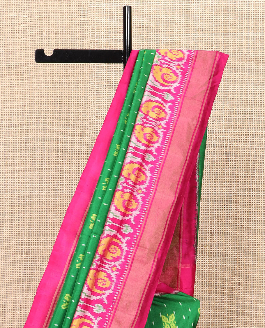 Green Ikkat silk saree features floral Ikkat buttas, highlighted with a contrast Ikkat woven border, a hazily woven Ikkat patterned pallu, and a contrast blouse
