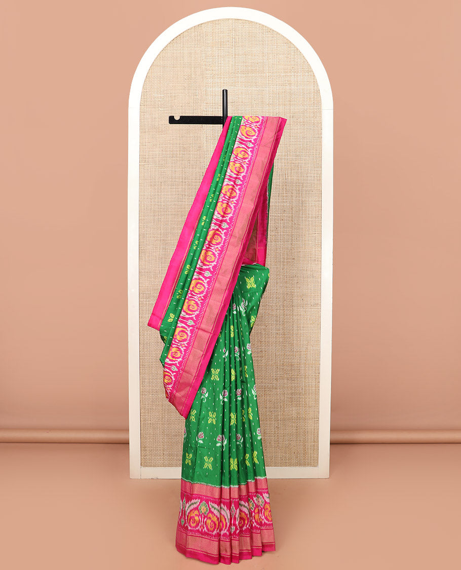 Green Ikkat silk saree features floral Ikkat buttas, highlighted with a contrast Ikkat woven border, a hazily woven Ikkat patterned pallu, and a contrast blouse
