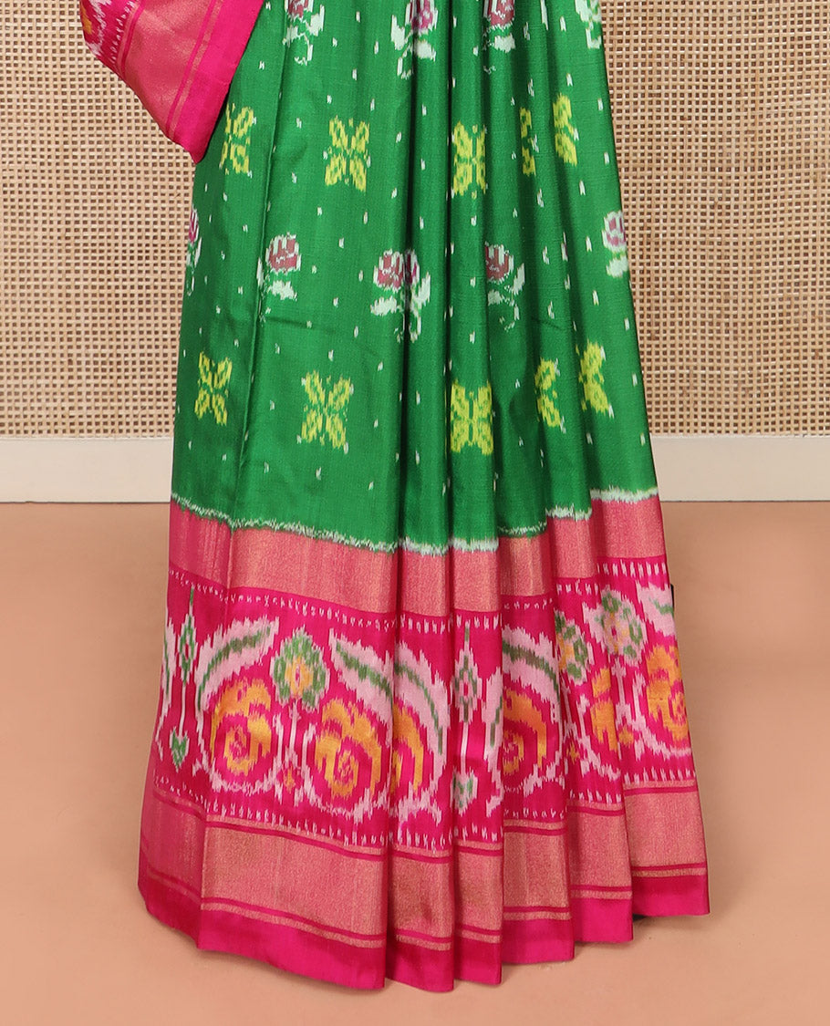 Green Ikkat silk saree features floral Ikkat buttas, highlighted with a contrast Ikkat woven border, a hazily woven Ikkat patterned pallu, and a contrast blouse