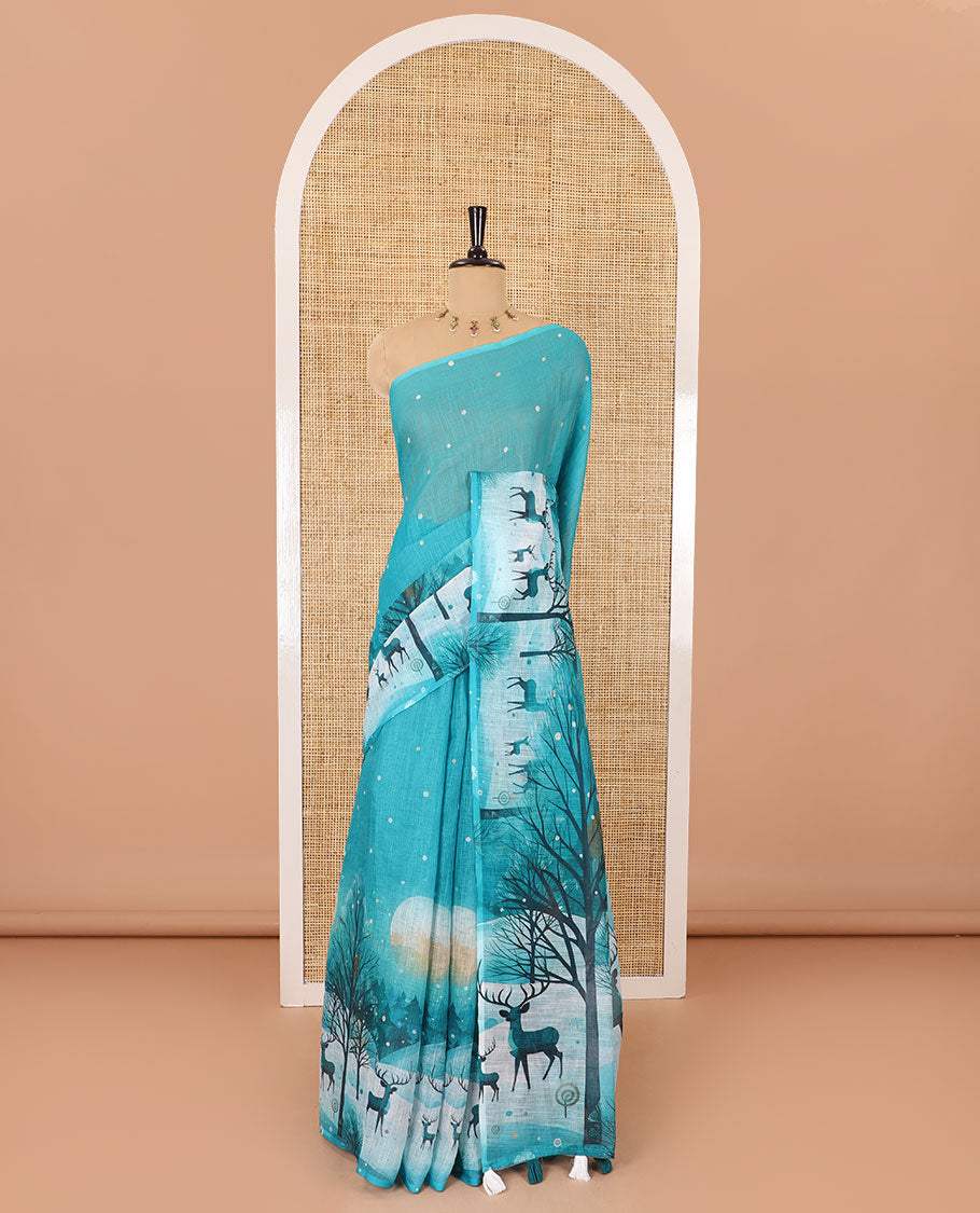 Borderless teal blue Christmas-theme Snow-fall, moon, trees, and deer motifs printed linen cotton saree with a contrast printed blouse