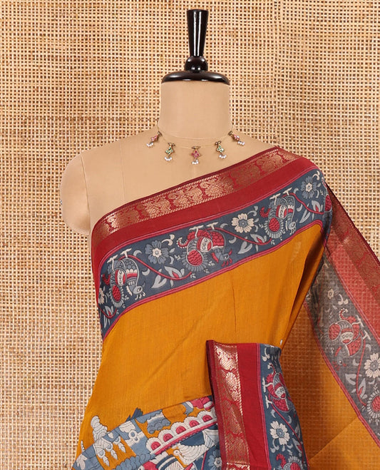 Mustard kalamkari ancient human figurines machine-printed muslin cotton saree, contrast traditional design zari border, kalamkari printed pallu, and contrast floral motifs and zari bordered blouse
