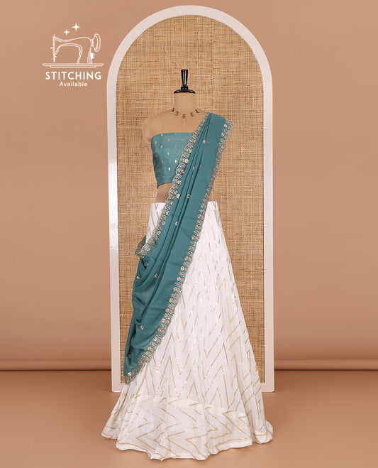 Cream-teal blue half-saree, gold chevron striped nylon viscose crepe skirt, contrast diamond buttas blouse, and  a contrast scallop floral-theme embroidered dhavani