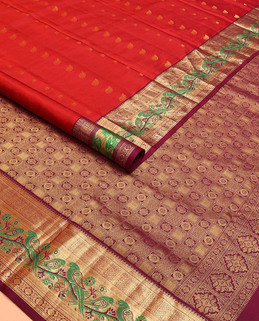 Orange Vasundhara Silk Mix Saree Decorated with Zari Buttas, Features Contrast Border Complemented with Thilakam, Banaras, Kathir, Mayil Kann, and Meenakari Parrot Motifs, a Pallu with Intricate Kanchi Motifs, Paired with a Contrast Blouse