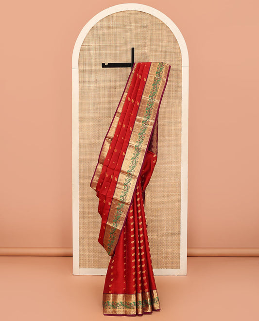 Orange Vasundhara Silk Mix Saree Decorated with Zari Buttas, Features Contrast Border Complemented with Thilakam, Banaras, Kathir, Mayil Kann, and Meenakari Parrot Motifs, a Pallu with Intricate Kanchi Motifs, Paired with a Contrast Blouse