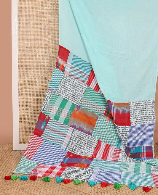 Borderless celeste blue plain khadi cotton saree, contrast kaleidoscope-colored patchwork style pallu of micro-checks, ikkat, and hindi typography designs with colorful tassels