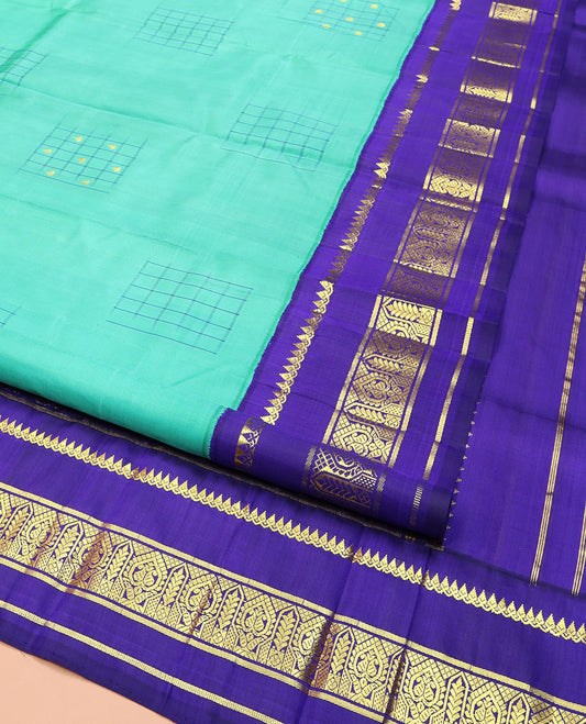 Turquoise Kanchipuram Silk Saree, Subtly Sparkled with Checked Buttas on Its Body, Complemented by a Contrast One-Sided Korvai Border of Thilakam Mokku, and Manga Designs, Pallu of Peacock Chariot Designs, and Comes Without a Blouse