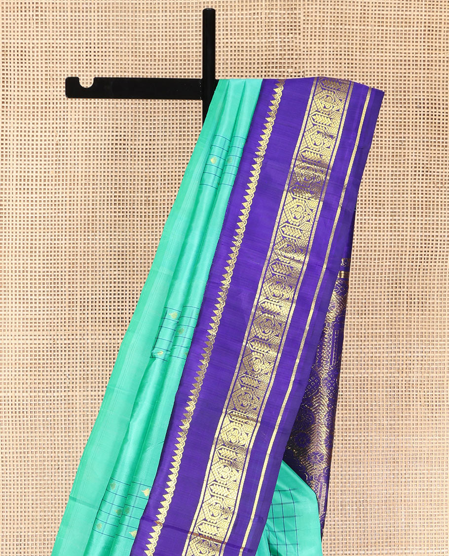 Turquoise Kanchipuram Silk Saree, Subtly Sparkled with Checked Buttas on Its Body, Complemented by a Contrast One-Sided Korvai Border of Thilakam Mokku, and Manga Designs, Pallu of Peacock Chariot Designs, and Comes Without a Blouse