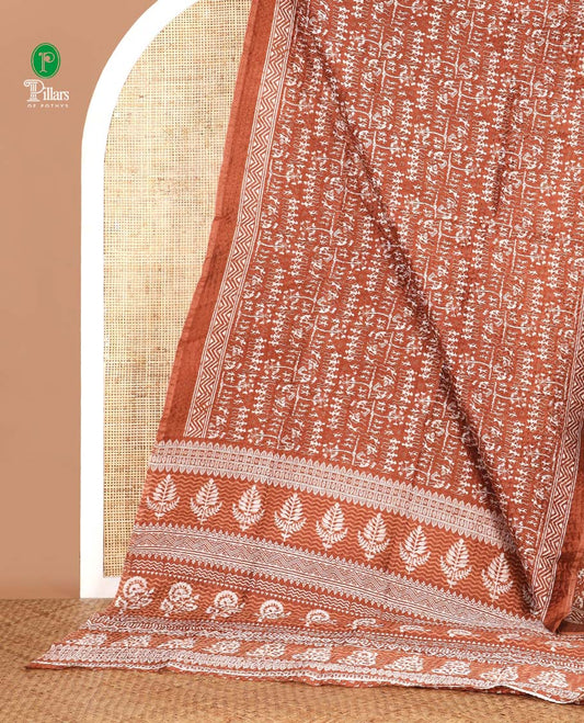 Rust batik-style warli printed Litch crushed saree, batik chevron border, floral-geometric printed pallu & triangle motif blouse