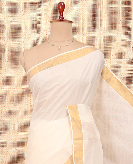 Cream Kerala Cotton Saree, Ornamented with Zari Buttas All Over Its Body, a Zari Bavanji Border, Pallu of Intricate Designs, and Paired with a Matching Blouse