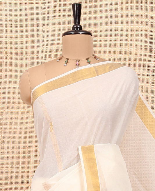Cream Kerala Cotton Saree, Enlivened with Zari Stripes All Over Its Body, a Subtle Bavanji Border, Pallu Depicts Peacock Designs, and Paired with a Matching Blouse
