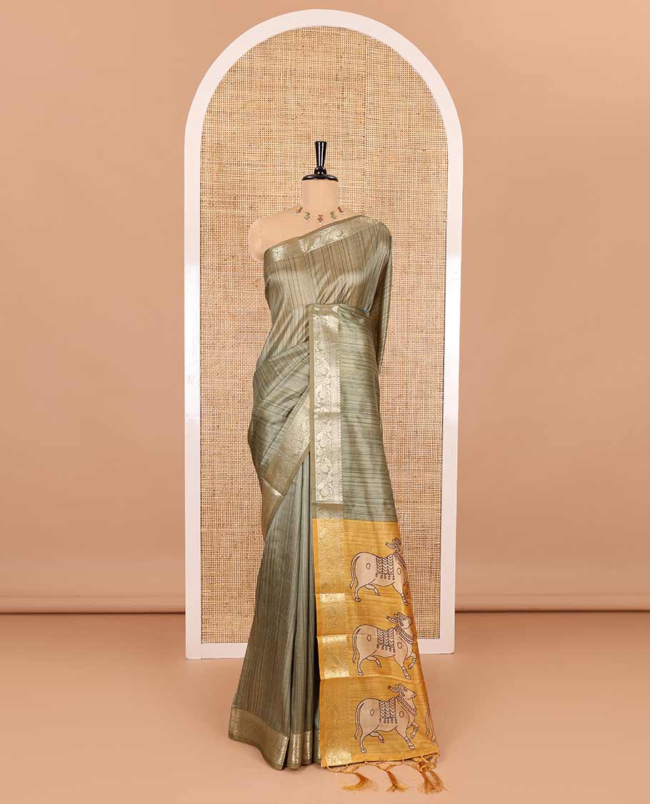 Olive green striped semi-tussar saree, traditional zari border of floral creeper designs, contrast pallu of Pichwai cow print, and contrast Pichwai cow printed blouse