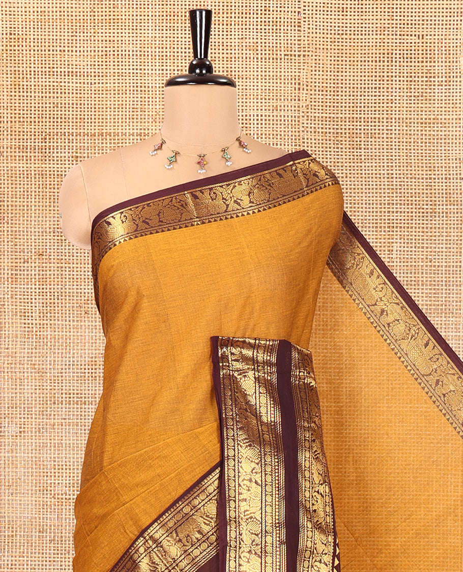 Mustard Plain Chettinad Cotton Saree, Complemented by a Contrast Rettai Pettu Zari Maroon Border of Temple, Coin, Elephant, and Peacock Designs, Subtly Striped Pallu, and Paired with a Matching Blouse