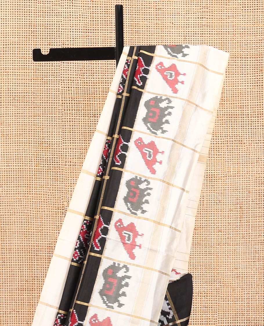Black Ikkat Silk Saree, Impeccably Styled with Patola-Style Parrot-Elephant Butta Enclosed Checks on Its Body, Complemented by a Contrast Patola-Style Parrot-Elephant Butta Enclosed Border, Pallu of the Same Motifs, and Paired with a Contrast Blouse
