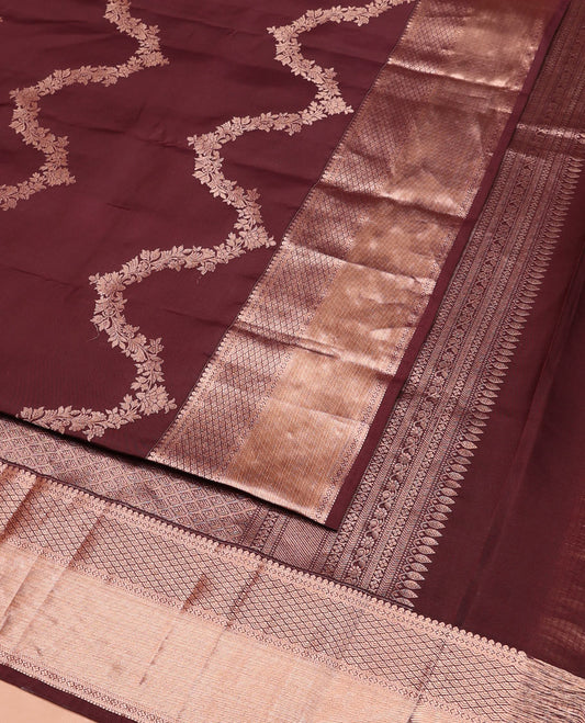 Brown Vasundhara Silk Saree Elegantly Sparkled with Floral Jaal Design All Over Its Body, Complemented by a Zari Border of Thilakam Mokku, Lavangam, Kathir, and Jaal Designs, Pallu Depicting Zari Jaal Designs, and Paired with a Matching Blouse