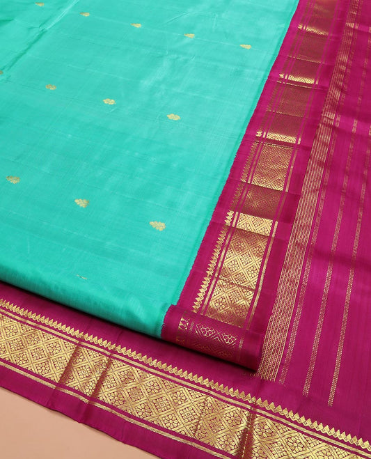 Turquoise Kanchipuram Silk Saree Bedecked with Zari Buttas All Over Its Body, Complemented by a Contrast One-Sided Korvai Border of Thilakam Mokku, Banaras, and Jaal Designs, Pallu of Zari Designs, and Comes Without a Blouse