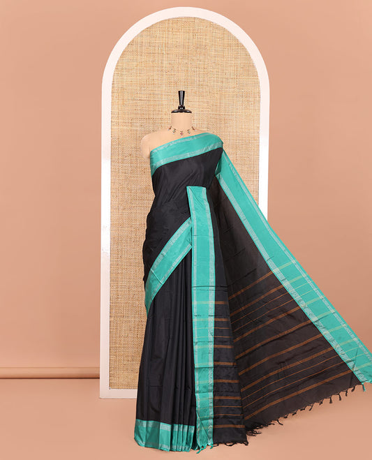 Black Plain Semi-Soft Silk Saree, Complemented by a Contrast Zari Striped Border, Pallu Features Stripes, and Paired with a Matching Blouse