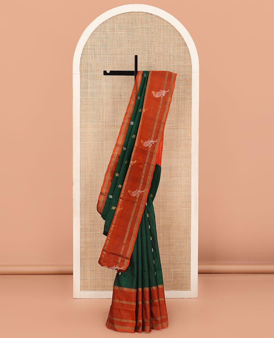Green Uppada Silk Saree Enlivened With Zari Buttas, Captivating Contrast Border Featuring Zari Stripes And Peacock Motifs, Pallu Depicting Rose Flower-Enclosed Mughal-Style Arches, And Paired With A Contrast Blouse