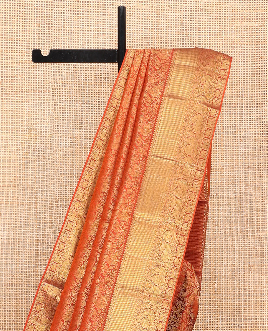 Orange Kanchipuram Wedding Silk Saree, Artfully Detailed with Jacquard Design on Its Body, Highlighted by Zari Border of Thilakam, Kuyil Kann, Diamond, Mayil, Yaali, and Yaanai Designs, Grand Jaal Pallu, and Paired with a Matching Blouse