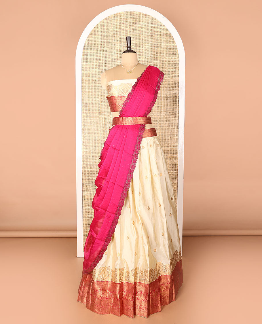 Cream-pink art-silk half-saree, zari buttas with contrast traditional design bordered skirt, a matching blouse, and scallop stone work dhavani