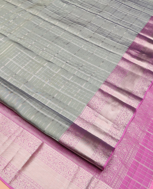Grey Vasundhara Lite Silk Mix Saree, Gracefully Embellished with Zari Checks On Its Body, Complemented by Contrast Border of Thilakam, Poun, Muthu, Kodi Visiry, and Mayil Kann Designs, Grand Pallu and Paired with a Contrast Blouse