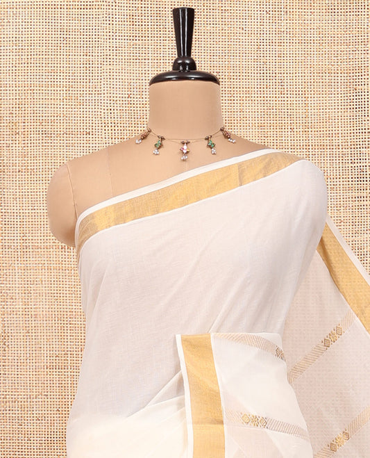Cream Kerala Cotton Saree, Woven with Zari Stripes All Over Its Body, a Subtle Bavanji Border, Pallu Depicts Intricate Designs, and Paired with a Matching Blouse