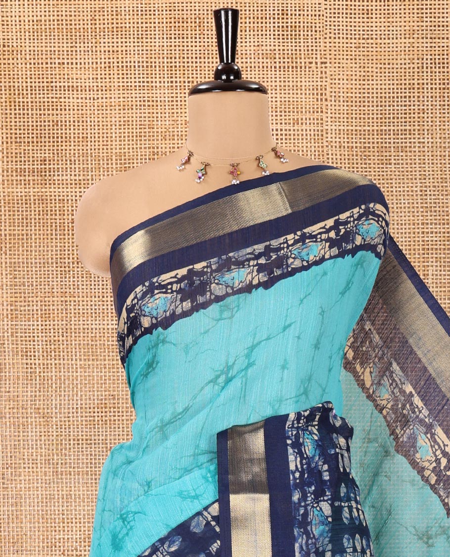 Rama Green Linen Cotton Saree, Adorned with Shibori Printed All Over Its Body, Complemented by a Contrast Batik Printed Zari Border, Floral Printed Pallu, and Paired with a Contrast Blouse