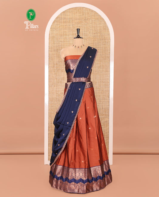 Orange and Navy Blue Semi-Banarasi Half-Saree Elevated with Zari Buttas on Its Skirt, Complemented by Contrast Traditional Zari Border of Chakram Designs, Paired with a Matching Blouse, and a Satin Georgette Embroidered Scallop Dhavani