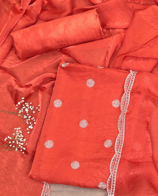Orange Material Churidar Set, Graced with Floral Embroidered Motif on Its Top, a Matching Bottom, and Scallop Embroidered Border Dupatta