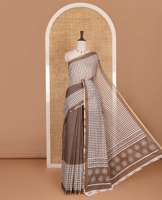 Brown plain and polka dots printed linen cotton saree with piping zari border, floral-geometric print pallu, and contrast flower buttas printed  blouse