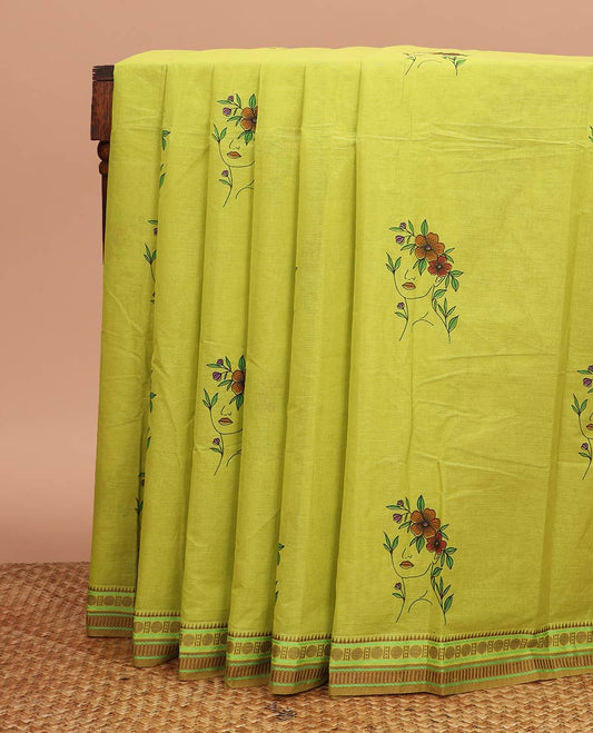 Green girl with a floral head motifs printed chirala cotton saree, traditional border, and pallu of stripes and kolam motifs print