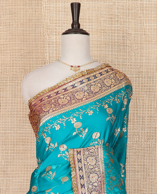 Blue floral buttas with stone work banarasi silk saree, contrast lace zari border of floral creeper designs, and pallu of Mughal-style intricate motifs