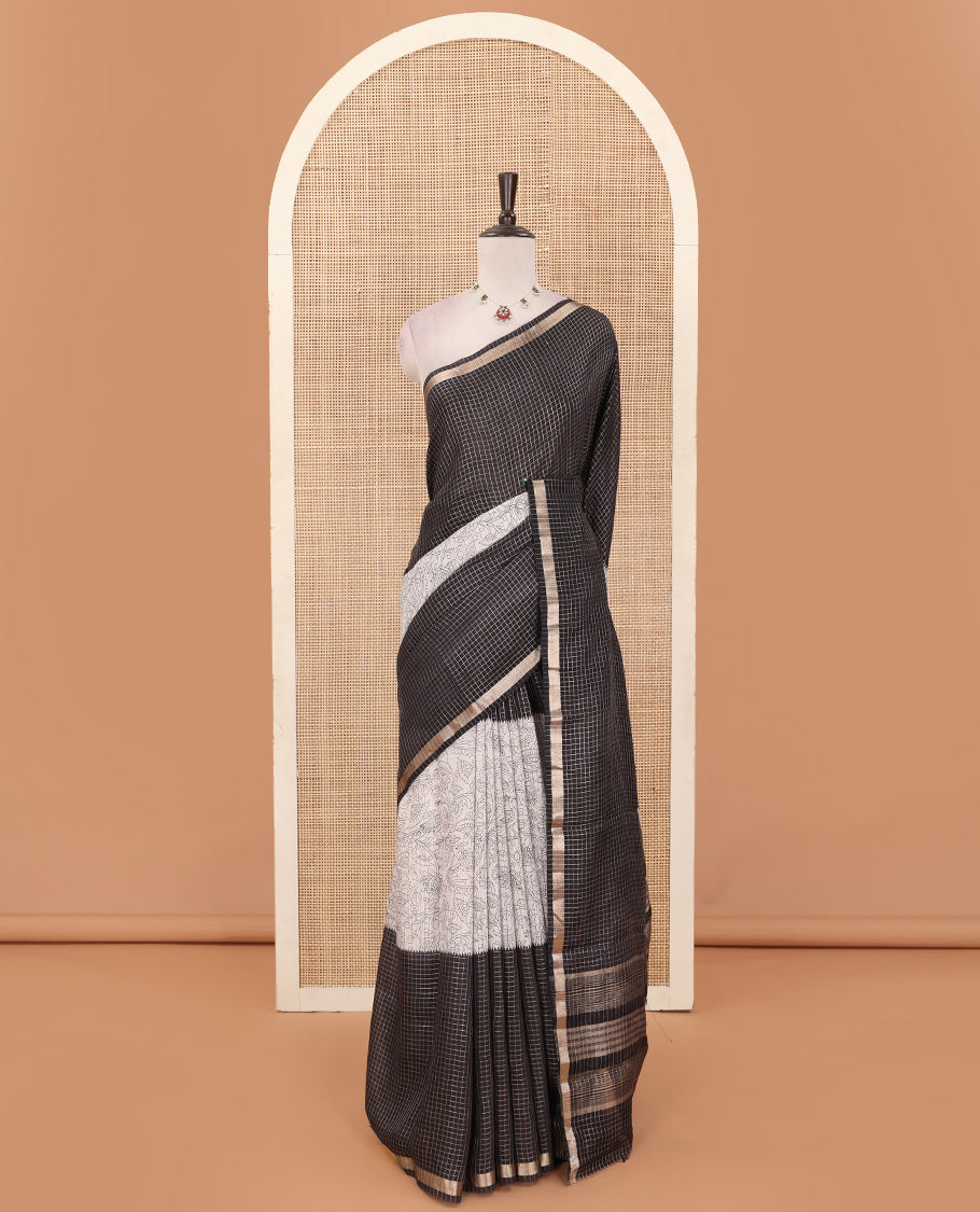Black and beige half-and-half style Muga silk saree adorned with zari micro-checks, and kalamkari flora-fauna prints, zari piping border, and zari striped pallu