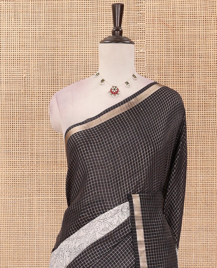 Black and beige half-and-half style Muga silk saree adorned with zari micro-checks, and kalamkari flora-fauna prints, zari piping border, and zari striped pallu