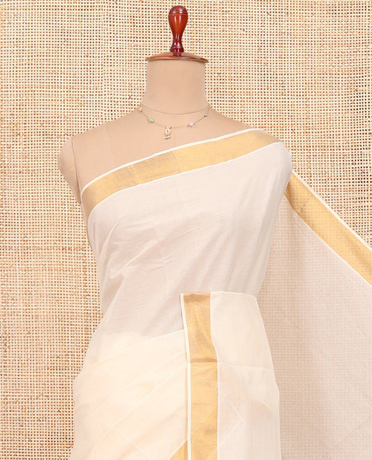 Cream Kerala Cotton Saree, Decked up with Zari Buttas All Over Its Body, a Zari Bavanji Border, Pallu of Intricate Designs, and Paired with a Matching Blouse