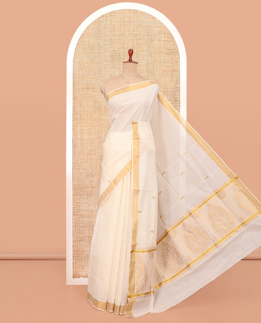 Cream Kerala Cotton Saree, Decked up with Zari Buttas All Over Its Body, a Zari Bavanji Border, Pallu of Intricate Designs, and Paired with a Matching Blouse