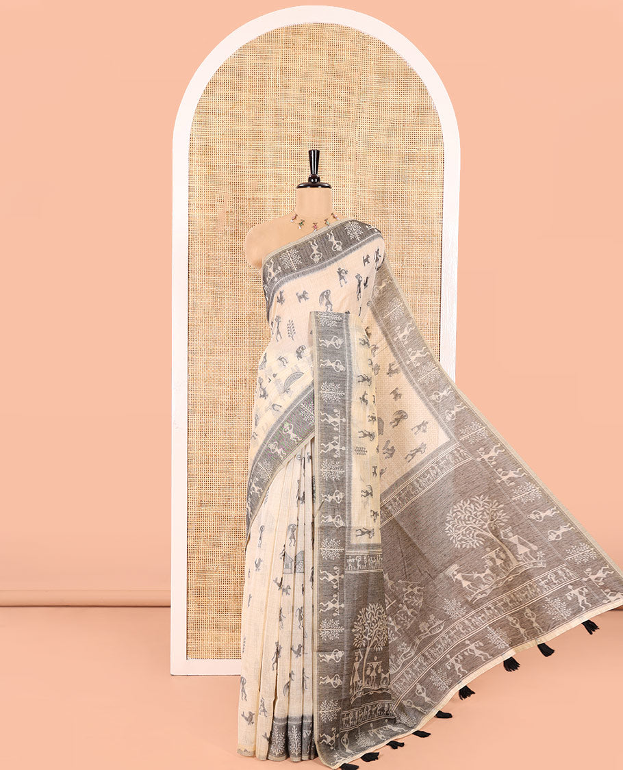 Chikku Munga Cotton Saree Bedecked with Threa Dwoven Warli-Village Theme Motifs All Over Its Body, Subtly Colored Contrast Warli Border, Pallu Depicting Warli Island, and Comes with a Matching Blouse