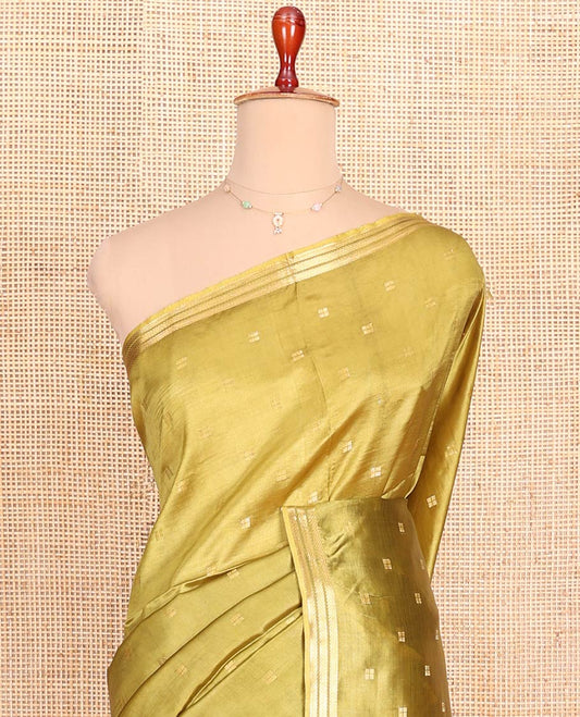 Green Banana Pith Saree Gracefully Embellished with Square-Shaped Zari Buttas, Subtly Woven Zari Piping Border, Pallu Gleamed Up with Zari Stripes, and Paired with a Matching Blouse