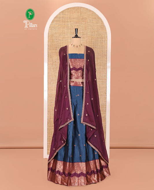 Peacock Blue and Purple Semi-Banarasi Half-Saree Elevated with Zari Buttas on Its Skirt, Complemented by Contrast Traditional Zari Border of Chakram Designs, Paired with a Matching Blouse, and a Satin Georgette Embroidered Scallop Dhavani