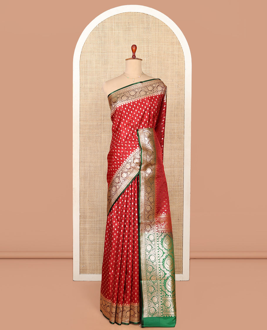 Red Semi-Banaras Saree, Richly Detailed with Zari Buttas on Its Body, Complemented by a Contrast Floral -Paisley Creeper Design Border, Intricately Designed Pallu, and Paired with a Contrast Blouse