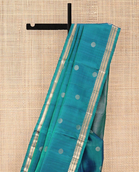 Blue Mayuri Soft Silk Saree, Highlighted with Rudraksham Buttas All Over Its Body, Subtle Border of Thazampoo Rekku, Muthu, and Kathir Designs, Sparsely Woven Jaal Pallu, and Paired with a Contrast Blouse