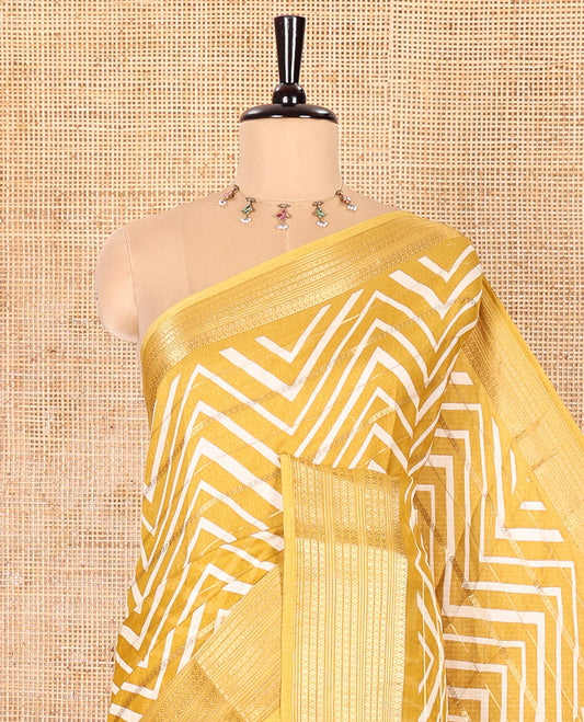 Yellow Moss Chiffon Saree Accentuated with Horizontal Stripes and Zig-Zag Stripes All Over Its Body, Highlighted by Traditional Zari Design Border, Pallu Depicts Butta Enclosed Checks, and Paired with a Matching Blouse