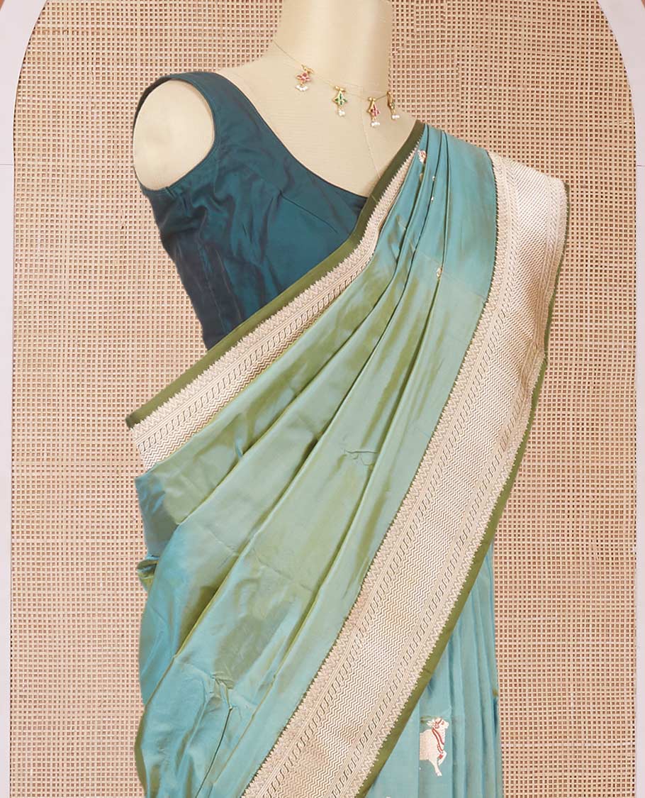 Green dual-shaded katan silk saree with pichwai cow motifs, contrast zari border & pallu features intricate designs