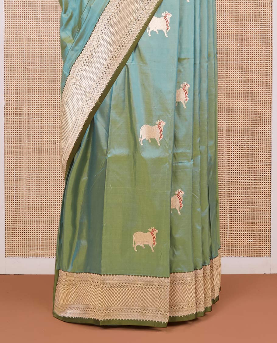 Green dual-shaded katan silk saree with pichwai cow motifs, contrast zari border & pallu features intricate designs