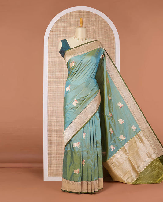 Green dual-shaded katan silk saree with pichwai cow motifs, contrast zari border & pallu features intricate designs