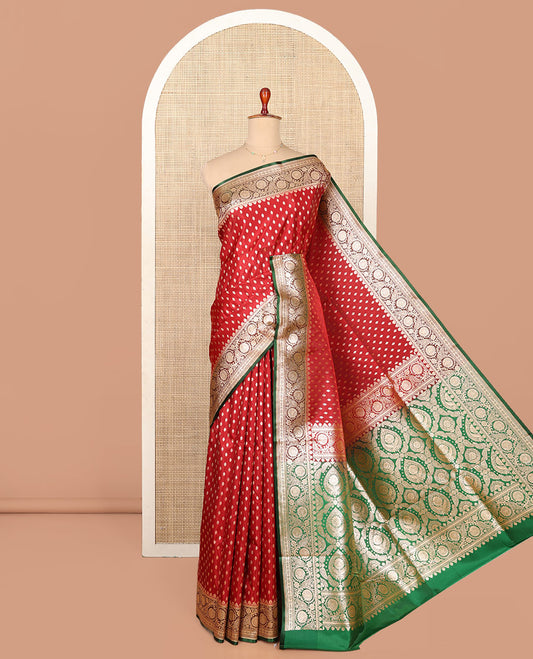 Red Semi-Banaras Saree, Richly Detailed with Zari Buttas on Its Body, Complemented by a Contrast Floral -Paisley Creeper Design Border, Intricately Designed Pallu, and Paired with a Contrast Blouse